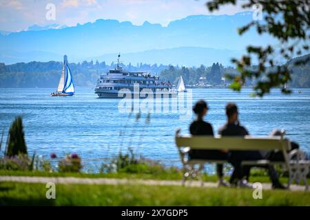 20 mai 2024, Bade-Württemberg, Überlingen am Bodensee : le navire à passagers Stuttgart navigue sur le lac de Constance jusqu'à l'embarcadère, tandis qu'au premier plan un couple est assis sur un banc dans le parc riverain. Photo : Felix Kästle/dpa Banque D'Images