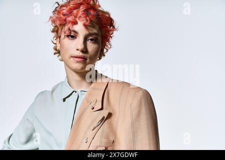 Femme extraordinaire avec des cheveux roux ardents se tient en toute confiance dans une veste élégante. Banque D'Images