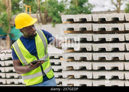 Ingénieur contrôle de qualité dans la fabrication de moulage de béton préfabriqué vérifiant les produits de qualité standard site de construction extérieur, travailleur noir africain Banque D'Images