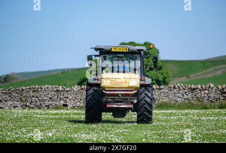 Agriculteur épandant de l'engrais sur un pré de foin traditionnel dans les Yorkshire Dales à l'aide d'un tracteur Hurlimann et d'un épandeur Teagle fert. Yorkshire du Nord, Banque D'Images