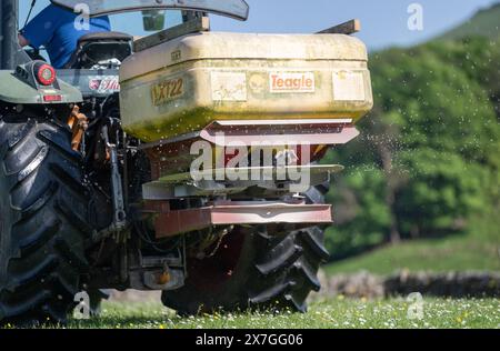 Agriculteur épandant de l'engrais sur un pré de foin traditionnel dans les Yorkshire Dales à l'aide d'un tracteur Hurlimann et d'un épandeur Teagle fert. Yorkshire du Nord, Banque D'Images