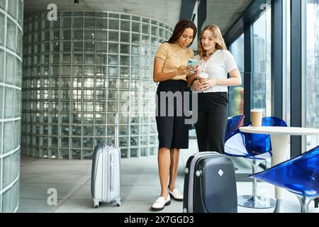 Deux collègues multiculturels debout côte à côte dans un hall d'hôtel lors d'un voyage d'affaires. Banque D'Images