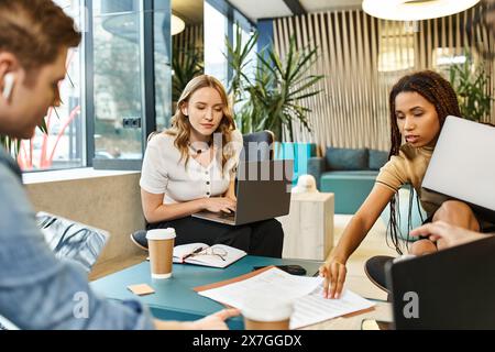 Un groupe diversifié de professionnels travaillant en collaboration sur des ordinateurs portables à une table d'espace de travail moderne. Banque D'Images