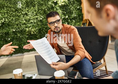 Un groupe de collègues assis autour d'une table, discutant des documents et collaborant sur des idées pour leur équipe de démarrage dans un environnement d'affaires moderne. Banque D'Images