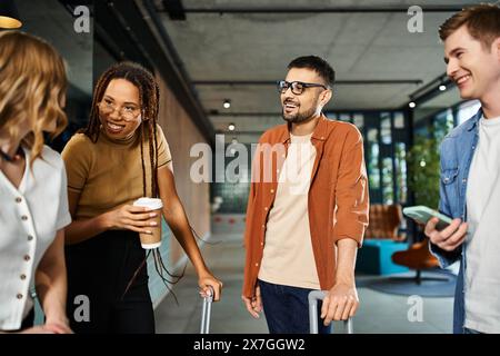 Des collègues multiculturels en tenue décontractée se tiennent en cercle dans le hall d'un hôtel lors d'un voyage d'affaires, engagés dans la conversation. Banque D'Images