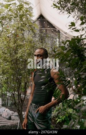 Un homme afro-américain sophistiqué se tient au cœur d'une forêt luxuriante. Banque D'Images