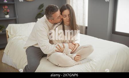 Un couple aimant profite d'un moment tendre ensemble dans le confort de leur chambre moderne. Banque D'Images