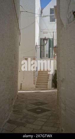 Une ruelle étroite et pavée à locorotondo, pouilles, italie, avec des bâtiments blanchis à la chaux et un escalier menant à une entrée résidentielle avec g Banque D'Images