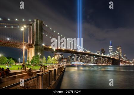 New York City Tribute in Light, commémoration du 11 septembre. Vue nocturne de deux colonnes de lumière dans Lower Manhattan avec le pont de Brooklyn illuminé Banque D'Images