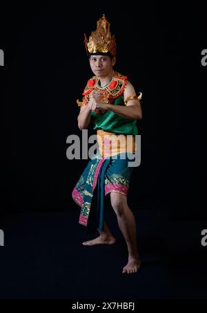 Homme indonésien exécutant une danse guerrière traditionnelle dans une tenue ornée et colorée Banque D'Images