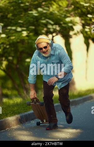 Skateboard homme senior avec joie, pose dynamique et expression enthousiaste reflétant l'esprit jeune. Banque D'Images
