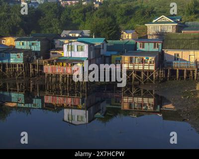 Palafitos colorés ou maisons de pêcheurs sur pilotis reflétés dans une crique au lever du soleil à Castro sur l'île de Chiloe, Chili. Banque D'Images
