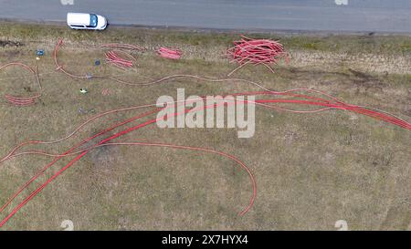 Photographie par drone de travailleurs de la construction, machines industrielles posant un nouveau pipeline près d'une route pendant la journée nuageuse du printemps Banque D'Images