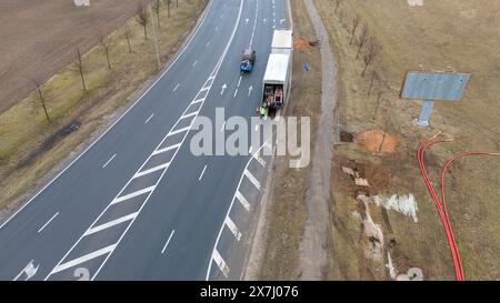 Photographie par drone de travailleurs de la construction, machines industrielles posant un nouveau pipeline près d'une route pendant la journée nuageuse du printemps Banque D'Images