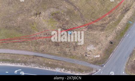 Photographie par drone de travailleurs de la construction, machines industrielles posant un nouveau pipeline près d'une route pendant la journée nuageuse du printemps Banque D'Images