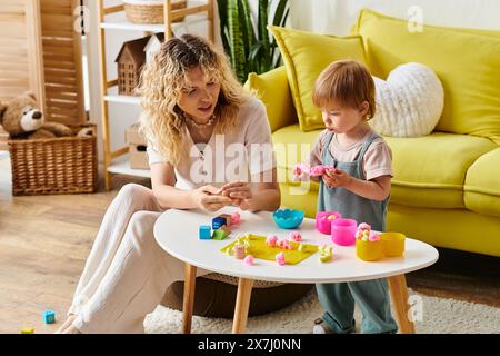 Mère bouclée et fille en bas âge jouant avec bonheur avec des jouets, pratiquant l'éducation Montessori à la maison. Banque D'Images