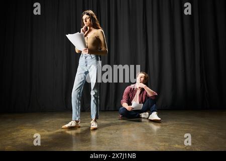 Une femme et un homme se tiennent confiants sur une scène de théâtre, répétant leurs rôles. Banque D'Images