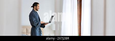 Un homme dans un peignoir utilisant un ordinateur portable. Banque D'Images