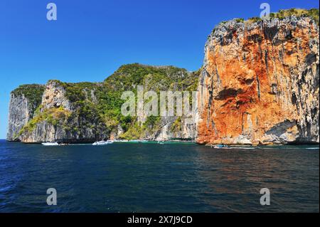 La magnifique baie de Tonsai a des eaux turquoises et est une ruche d'activité nautique. Les ferries vont et viennent, les yachts mouillent, les bateaux de plongée et d'excursion font des allers et retours transportant des passagers ou des marchandises. La baie est longue de près de 2 km des points extérieurs, avec de hautes falaises cédant la place à de petites plages habitées par des singes et avec des récifs coralliens bordant le côté ouest. Le côté est de la baie est moins profond, avec de grandes zones de corail et une série de plages et d'hôtels occupant le rivage. À l'embouchure de la baie, sur le côté est, se trouvent long Beach et Shark point, qui font face à Phi Phi Leh. Thaïlande. Banque D'Images