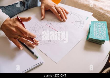 Un astrologue dessine avec un crayon sur une carte natale Banque D'Images