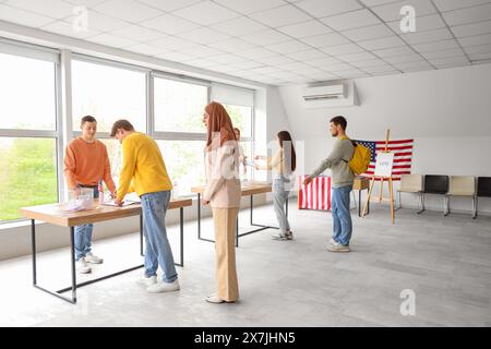 Vote des jeunes près des urnes avec drapeaux américains au bureau de vote Banque D'Images