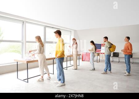 Vote des jeunes près des urnes avec drapeaux américains au bureau de vote Banque D'Images