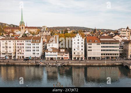 Le bord de la rivière Limmat de Zurich par une journée d'automne calme, avec de vieux bâtiments bordant les berges et la flèche de la bibliothèque centrale visible derrière Banque D'Images