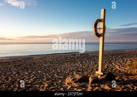 Bouée de sauvetage sur une plage de sable de la mer Baltique au Danemark près d'Idestrup pendant le beau lever du soleil Banque D'Images