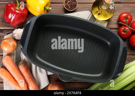 Pot noir avec des épices et des légumes sur la table en bois, plat Banque D'Images