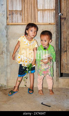 Mignons, petits, jeunes enfants Hmong, garçon et fille tenant un bouquet de fleurs cueillies dans un village de Chiang Khong, province de Chiang Rai, dans le nord de la Thaïlande Banque D'Images