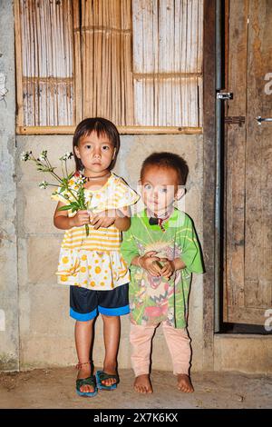 Mignons, petits, jeunes enfants Hmong, garçon et fille tenant un bouquet de fleurs cueillies dans un village de Chiang Khong, province de Chiang Rai, dans le nord de la Thaïlande Banque D'Images