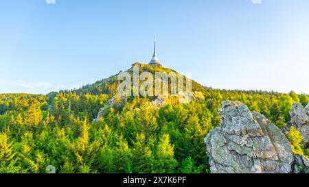 Jested Mountain en Tchéquie avec sa tour emblématique, entourée de forêts verdoyantes sous un ciel bleu clair par une soirée ensoleillée. Banque D'Images