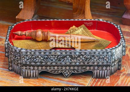 Le stylo avec un ensemble de plaques de talisman dans une boîte décorée, temple bouddhiste, Thaïlande. Banque D'Images