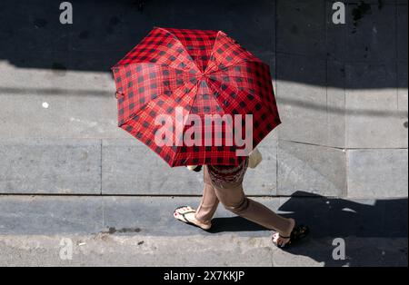 Un marcheur dans la rue de la ville se cache sous un parasol, Ho Chi Minh ville. Banque D'Images