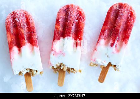 Trois popsicles au yaourt aux fraises maison sur de la glace pilée Banque D'Images
