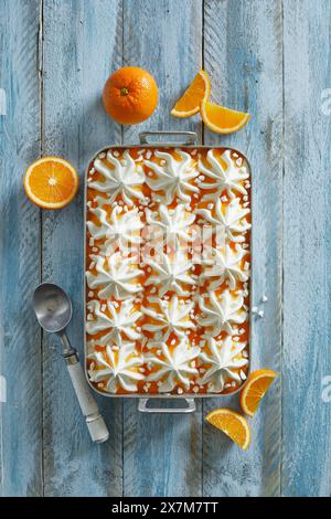 Dessert à la crème glacée fraîche vanille-orange fait maison avec des morceaux de meringue sur un fond en bois bleu Banque D'Images