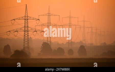 Algermissen, Allemagne. 21 mai 2024. Une ligne électrique à haute tension monte dans la lumière du matin dans le quartier de Hildesheim. La réforme prévue du marché européen de l'électricité devrait franchir le dernier obstacle mardi. À la fin de l'année dernière, les états membres de l'UE sont parvenus à un accord avec le Parlement européen sur la réforme, qui vise à mieux protéger les consommateurs contre la hausse des prix de l'électricité à l'avenir. Crédit : Julian Stratenschulte/dpa/Alamy Live News Banque D'Images