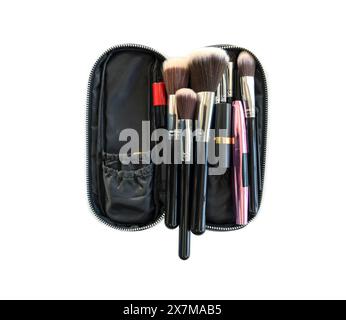 Un ensemble de diverses brosses de maquillage est soigneusement disposé dans un boîtier noir ouvert zippé. Studio tourné sur fond blanc. Isolé Banque D'Images