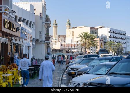 Muscat, Oman - 2 janvier 2024 : une scène de rue animée capture les habitants et les visiteurs au milieu de l'architecture traditionnelle, avec les tours emblématiques de la mosquée Banque D'Images