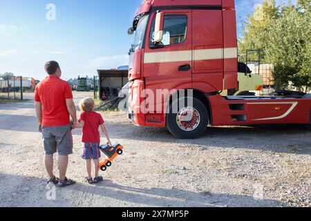 garçon et un homme debout, le dos contre la toile de fond de la cabine d'un tracteur-remorque Banque D'Images