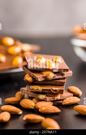 Barre de chocolat cassée avec des amandes sur une table noire. Banque D'Images