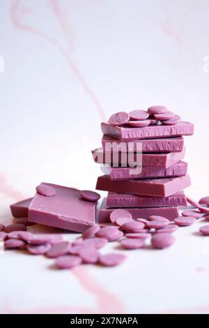 Chocolat rubis fabriqué à partir de variétés de fèves de cacao botaniques sélectionnées. Barres et boutons de fusion de palettes. Banque D'Images