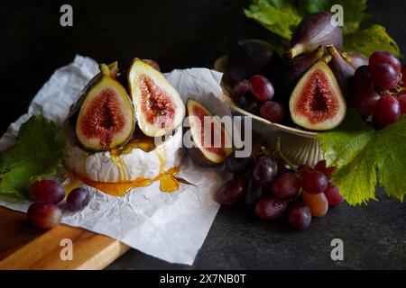 Fromage Brie servi avec figues, miel et raisins. Banque D'Images