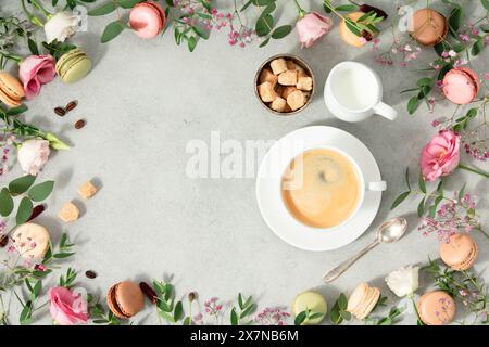 Tasse blanche de café et cadre fait de fleurs de printemps et de différents types de macarons à plat mettre en place l'espace de copie de maquette Banque D'Images