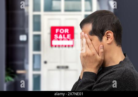 Homme extrêmement déprimé et triste au sujet de perdre sa clé de maison et de voir un signe pour la vente, concept immobilier Banque D'Images