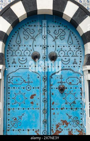 Conception détaillée d'une porte bleue traditionnelle dans le village tunisien de Sidi Bou Said, au sommet d'une falaise, surplombant la ville historique de Carthage et le golfe de Tunis. Banque D'Images