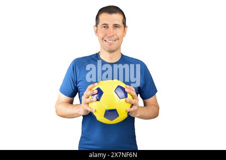 Homme jouant au football tenant le ballon jaune de football sur fond blanc avec un sourire heureux et cool sur le visage. Personne chanceuse. Banque D'Images