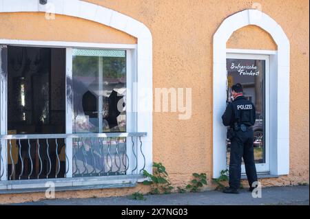 Hoppegarten, Allemagne. 21 mai 2024. Un policier obtient des preuves à la porte d'un restaurant à Hoppegarten. Une fenêtre du restaurant avait été brisée, la façade enduite et de l'acide butyrique distribué. Le restaurant avait récemment été le lieu d'une foire du livre de droite organisée par un politicien de l'AFD. Les pompiers ont été déployés avec une vingtaine de véhicules à cause de l'acide butyrique. Crédit : Christophe Gateau/dpa/Alamy Live News Banque D'Images