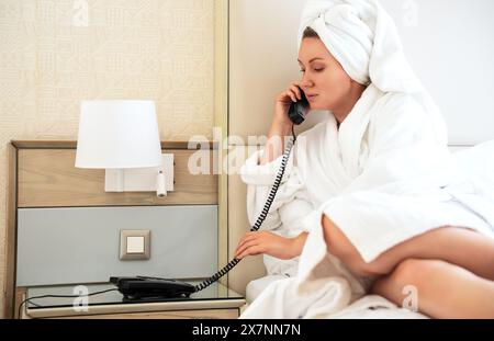 La femme appelle de sa chambre à la réception. Banque D'Images