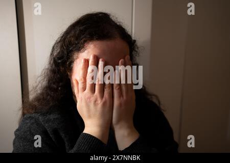 Femme désespérée pleurant dans une pièce sombre. Dépression, solitude et santé mentale en général. Banque D'Images